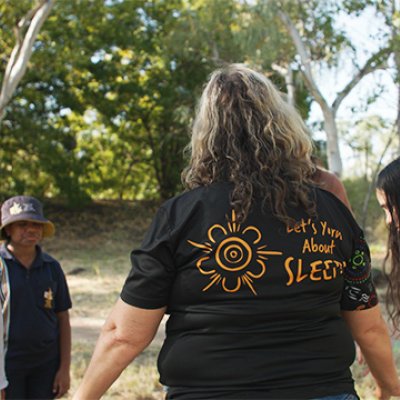 a group of people stand in a circle under trees with eyes closed